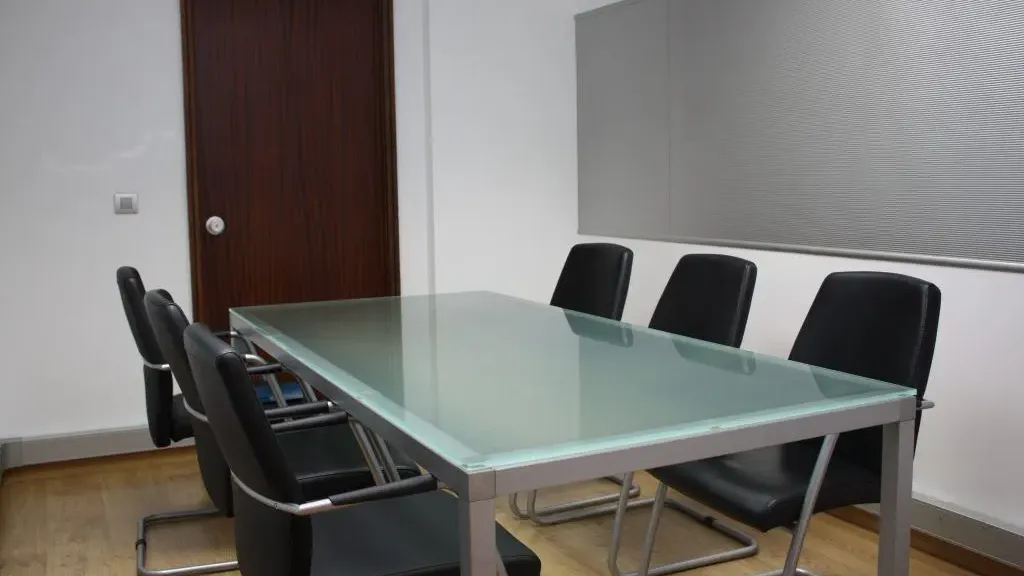 Sala de reunião com mesa de vidro e cadeiras pretas