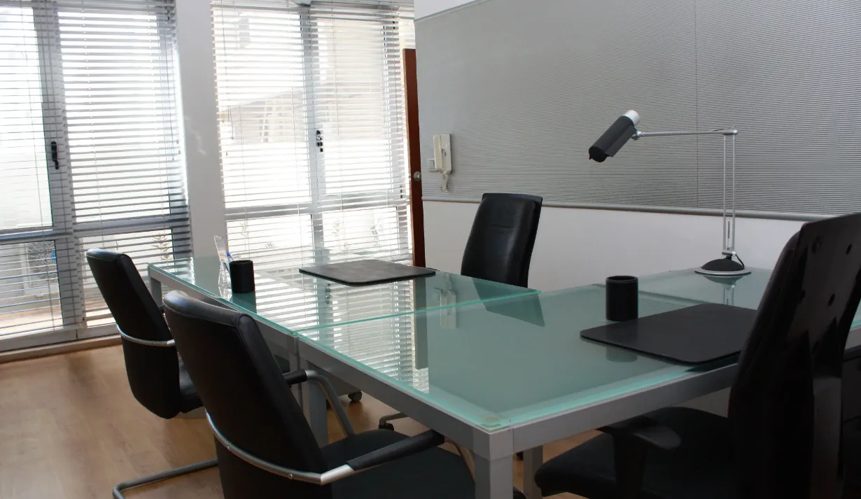 Sala com estores, mesa de vidro e cadeiras pretas